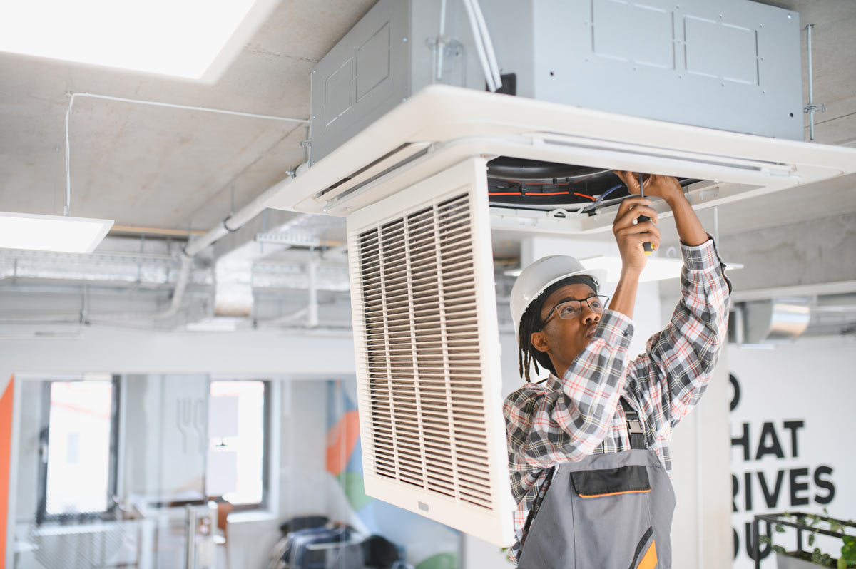 african-american-skilled-HVAC-technician-repairing-office-AC